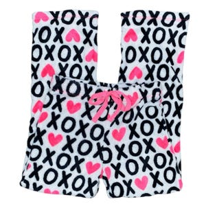以下が含まれることがあります： 白地に黒の「XOXO」パターンとピンクのハートが特徴のパジャマパンツ。 ピンクのドローストリングが付いており、柔らかくふわふわした素材で作られています。 快適な寝間着です。