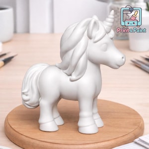 Könnte beinhalten: Eine weiße Einhornfigur mit Horn, Mähne und Schweif, die auf einer runden Holzbasis steht. Die Figur ist unbemalt und bereit zur individuellen Gestaltung. Das Bild enthält den Text "Print & Paint".