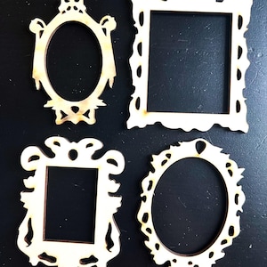 Könnte beinhalten: Vier dekorative Holzrahmen in verschiedenen Formen: zwei ovale und zwei rechteckige. Die Rahmen haben aufwendige, vintage-inspirierte Designs mit komplizierten Details. Das Holz hat eine helle, natürliche Farbe, und die Rahmen sind vor einem dunklen Hintergrund platziert.