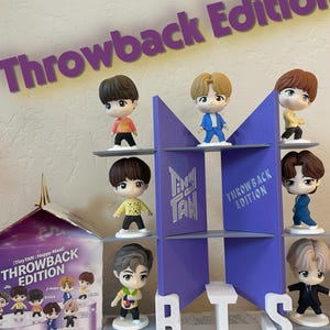 May include: A display of TinyTAN Happy Meal figurines in a purple and white display. The figurines are of various characters in different outfits. The display includes the text "Throwback Edition!" and "BTS".