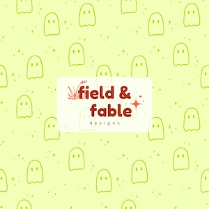 May include: A repeating pattern of light green ghost illustrations on a pale yellow background with small star shapes. A white rectangle with the words "field & fable designs" in red and white is in the center.