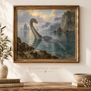 May include: A framed landscape painting depicting a long-necked plesiosaur swimming in a calm sea near rocky cliffs under a cloudy sky. The artwork is titled Wildermere Studios and features muted blue, green, and golden tones in a vintage style.