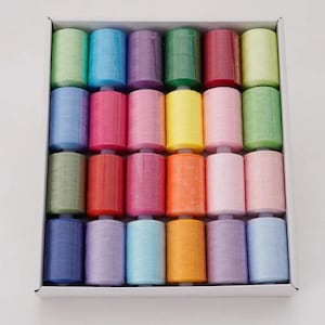 May include: A box of colorful thread spools in various shades, including green, blue, pink, purple, and orange. The spools are neatly arranged in rows within a white box, offering a vibrant display of sewing supplies.