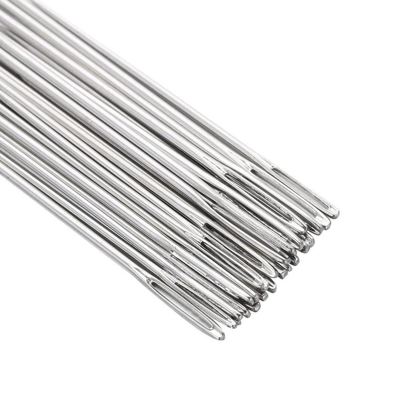 May include: A close-up shot of a collection of silver sewing needles. Each needle is slender, featuring a small eye at one end and a sharp point at the other. The needles are arranged diagonally against a white backdrop.