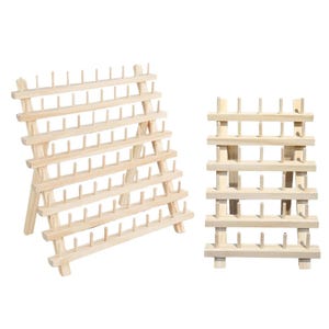 Puede incluir: Dos soportes de madera para carretes de hilo. Uno es un diseño en forma de A con múltiples filas de clavijas para sujetar los carretes. El otro es un soporte rectangular más pequeño con varias filas de clavijas. Ambos son de madera clara.
