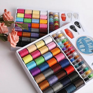 May include: A sewing kit with a variety of colorful thread spools, needles, and other sewing accessories. The thread spools are arranged in rows by color, including pink, yellow, blue, and brown. The kit is in a white plastic container.