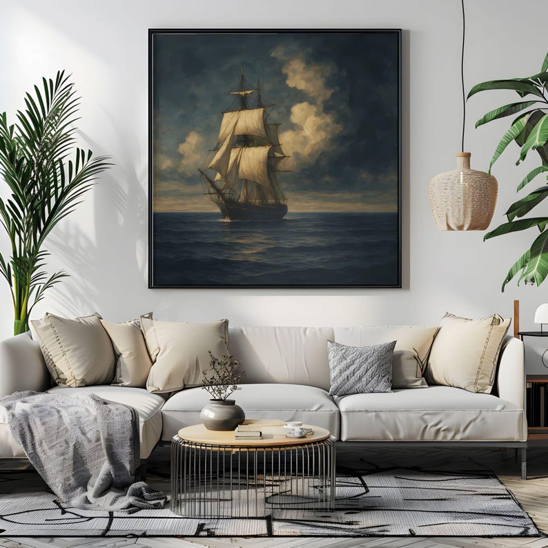 May include: A framed nautical painting depicts a tall ship sailing on a dark blue sea under a cloudy sky. The artwork features a black frame and is displayed above a white sofa with beige pillows, enhancing the room's decor.