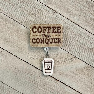 以下が含まれることがあります： ベージュの背景に茶色の文字で「COFFEE then CONQUER」と書かれたバッジリール。テキストの下には、茶色の輪郭を持つ白いコーヒーカップのグラフィックがあります。