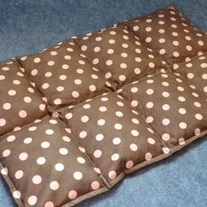May include: A brown and pink polka dot quilted throw pillow. The pillow is made of fabric with a quilted design and is filled with a soft, comfortable material.