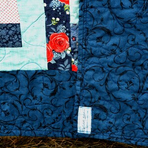 May include: A blue quilt with a floral pattern and a label that says "Cozy Loft Creations".