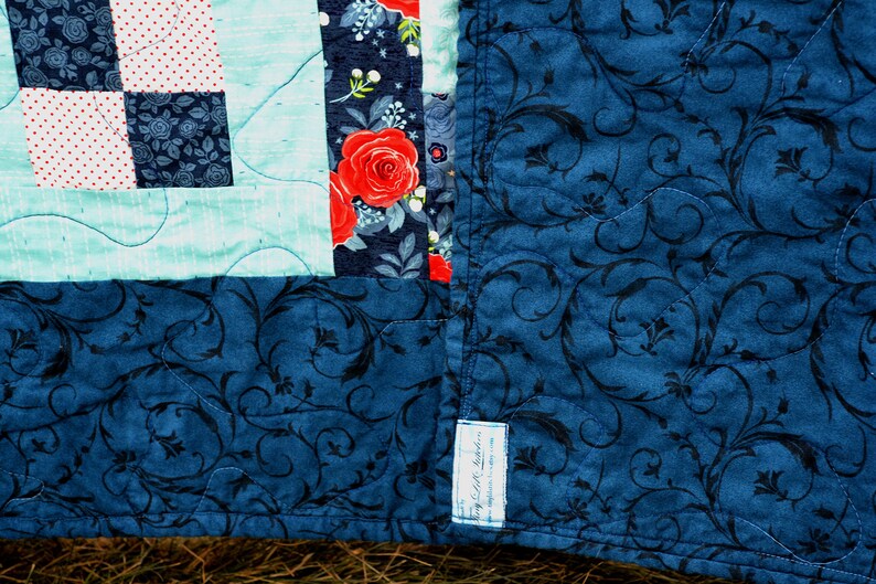 May include: A blue quilt with a floral pattern and a label that says "Cozy Loft Creations".
