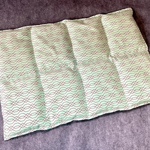 May include: A green and brown patterned pillow with a quilted design. The pillow is made of soft fabric and has a rectangular shape.