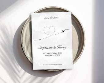 May include: A white wedding invitation card with the text "Save the date!" and the names "Stephanie & Harry". The card features a heart-shaped dotted line with a plane, and the date "12th September 2026, Majorca, Spain".