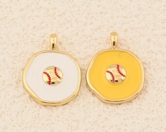 Pode incluir: Dois pingentes com tema de beisebol. Um tem fundo branco, o outro é amarelo. Ambos têm uma borda dourada e um desenho de beisebol no centro com costuras vermelhas. Os pingentes são provavelmente para fazer joias.