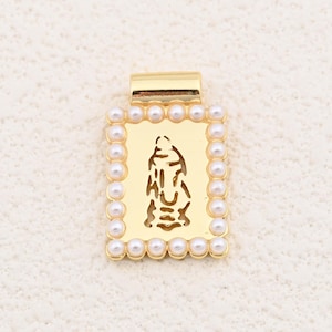 May include: Gold-tone pendant with a rectangular frame, featuring a cutout religious figure and a border of small, round, white pearls. The pendant has a rectangular bail at the top for a chain.