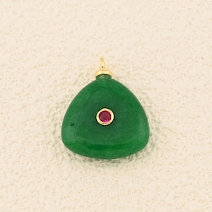 May include: A triangular, emerald green pendant with a small, round, red gemstone in the center. The pendant has a gold-colored bail at the top for attaching to a chain. The gemstone is set in a gold-colored bezel.