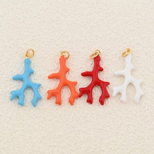 Könnte beinhalten: Vier farbige Anhänger in Korallenform in Blau, Orange, Rot und Weiß. Jeder Anhänger hat oben eine goldfarbene Schlaufe zum Befestigen an Schmuck. Die Anhänger sind so gestaltet, dass sie Korallenästen ähneln.