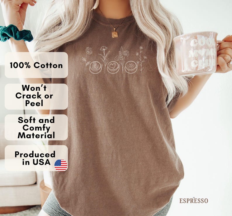 May include: Espresso-colored t-shirt with a floral and coffee cup design. The shirt features the text "100% Cotton", "Won't Crack or Peel", "Soft and Comfy Material", and "Produced in USA". The word "ESPRESSO" is also visible.