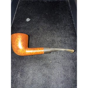Pode incluir: Um cachimbo de tabaco clássico com uma haste curva e uma tigela arredondada. O cachimbo é feito de madeira castanha clara com uma haste e boquilha castanhas escuras. A palavra "HYS" está impressa na lateral do cachimbo.