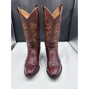 May include: A pair of brown cowboy boots with a textured, reptile-like pattern on the lower portion and decorative stitching on the upper shaft. The boots have pointed toes and a classic Western design.