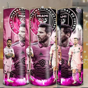 May include: A set of three stainless steel tumblers featuring a pink and purple design with a soccer player. The tumblers have the words "CLUB INTERNACIONAL DE FUTBOL MIAMI" and the team logo. The player is wearing a pink uniform.