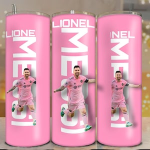 May include: Pink stainless steel tumbler featuring a photo of a soccer player in a pink uniform. The name "Lionel" is printed in white at the top, with the word "ME" in large white letters below the name. A silver straw is included.