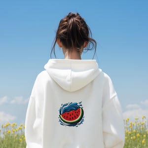 May include: A white hoodie with a watermelon design on the back. The design shows a red watermelon slice with blue water splashes. The background is a blue sky with yellow flowers.
