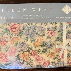 May include: Eileen West full fitted sheet set in a plastic package. The sheet set features a floral pattern with pink, purple, and yellow roses on a cream background. The packaging includes the brand name, fabric details, and a white ribbon.