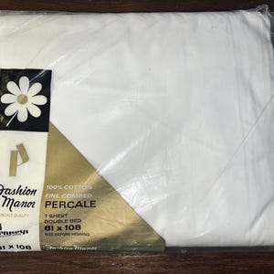 May include: A packaged white percale double bed sheet from Fashion Manor. The packaging includes the brand logo with a daisy and the text "100% Cotton Fine Combed Percale". The sheet measures 81 x 108 inches.