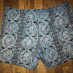 May include: Blue and black patterned swim trunks with a geometric design.