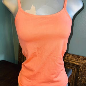 May include: A coral colored sleeveless tank top with thin straps.