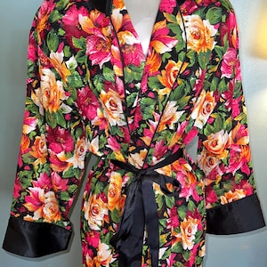 May include: A black and green floral print robe with a black satin trim and tie. The robe has a V-neck and long sleeves.