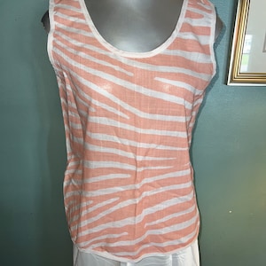 May include: A sleeveless top with a white and peach zebra print. The top has a scoop neck and is made of a lightweight fabric.