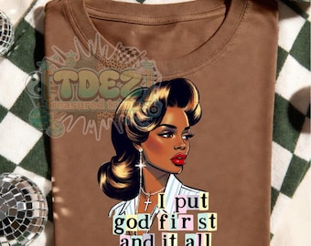 May include: Brown t-shirt featuring a stylized illustration of a woman with dark hair and red lipstick. The text "I put god first and it all worked out" is below the illustration. The shirt is on a green and white checkered surface.