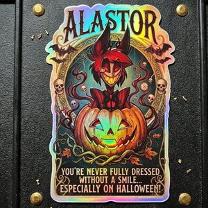 Puede incluir: Una pegatina holográfica que muestra a un personaje llamado Alastor saliendo de una calabaza. El diseño incluye murciélagos, calaveras y el texto: ALASTOR, YOU'RE NEVER FULLY DRESSED WITHOUT A SMILE... ESPECIALLY ON HALLOWEEN! La pegatina tiene un acabado metálico.