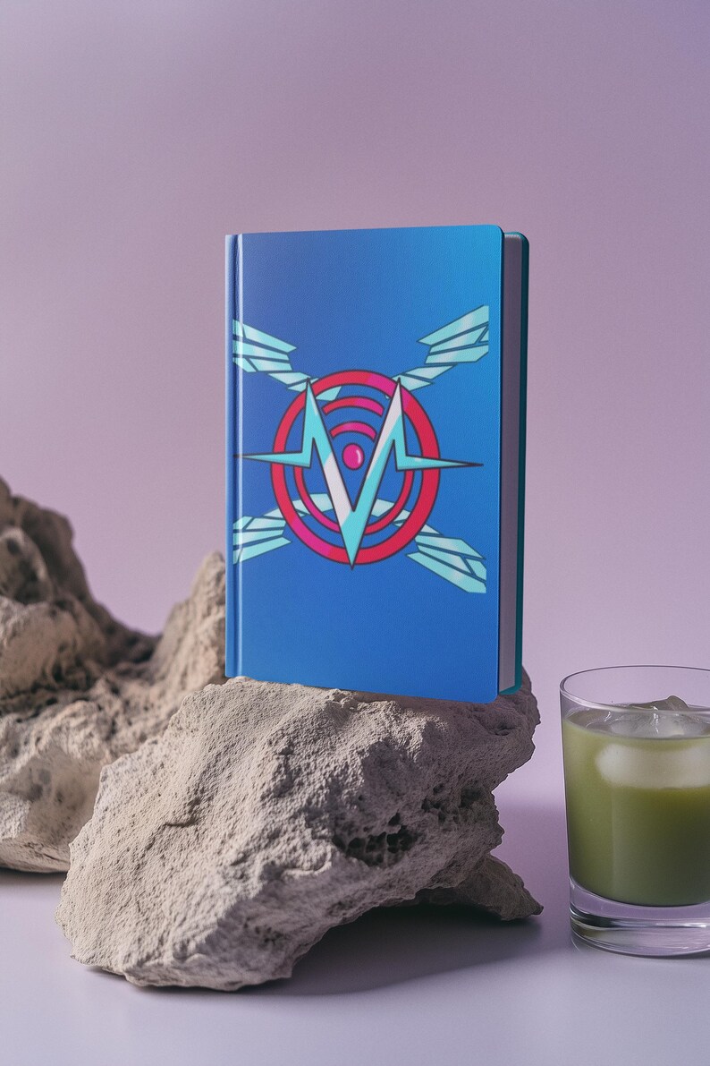May include: A blue notebook with a geometric design featuring a red circle, a white "M", and light blue wings. The notebook is resting on a light-colored rock, with a glass of green liquid with ice in the background.