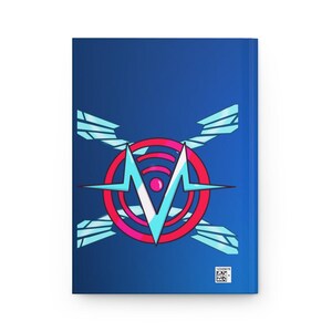 May include: A blue journal with a graphic design on the cover. The design features a stylized letter "M" in light blue, a red circle with pink accents, and light blue wing-like shapes. A barcode is visible.