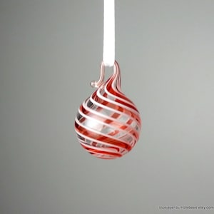 以下が含まれることがあります： 渦巻き模様の赤と白のストライプのガラス製のクリスマスオーナメント