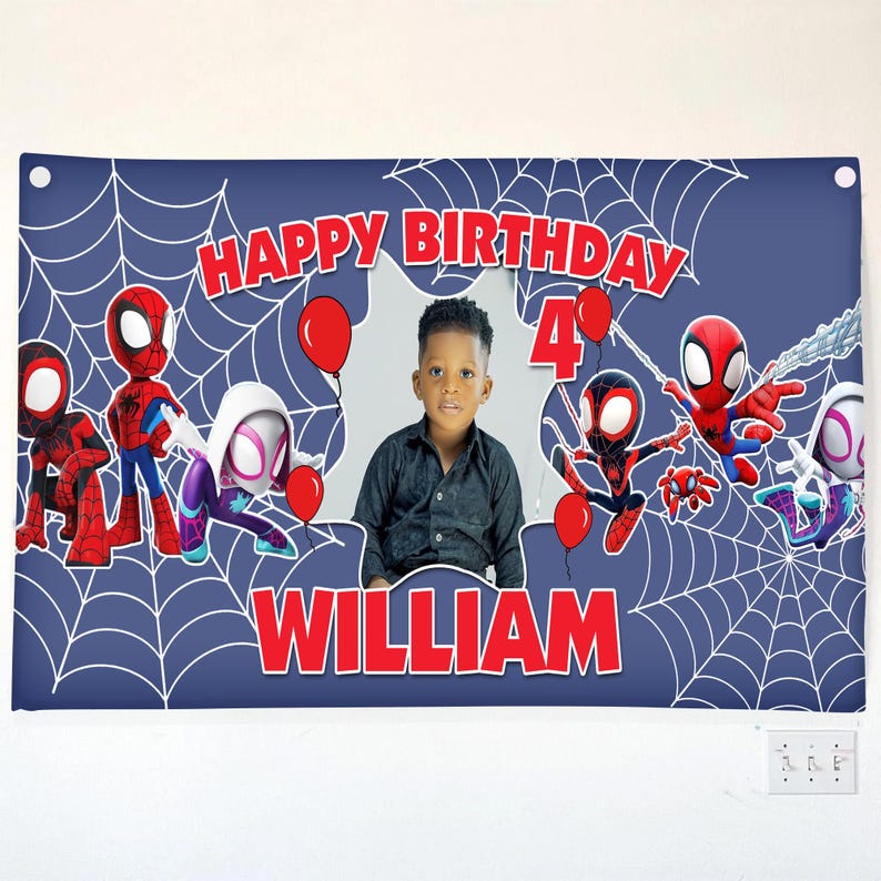 Może przedstawiać: Prostokątny niebieski baner urodzinowy z białymi wzorami pajęczyn, czerwonym napisem HAPPY BIRTHDAY i WILLIAM, cyfrą 4, czerwonymi balonami i postaciami pająk&oacute;w. Centralne wycięcie zawiera zdjęcie małego dziecka.