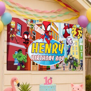 Puede incluir: Una pancarta de cumplea&ntilde;os rectangular que muestra una colorida escena urbana con varios superh&eacute;roes, incluidos Iron Man, Hulk y Spider-Man. El centro muestra un &oacute;valo azul con el texto amarillo HENRY y el texto blanco BIRTHDAY BOY.