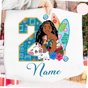 Puede incluir: Tela blanca con una colorida ilustraci&oacute;n de un personaje de dibujos animados, un cerdo y un gallo. El n&uacute;mero 2 es en azul y naranja, con la palabra "Name" en cursiva debajo.