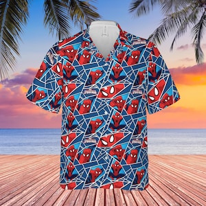 K&ouml;nnte beinhalten: Kurz&auml;rmeliges Hemd mit einem sich wiederholenden Muster von Spider-Man in Rot und Blau. Das Hemd hat einen wei&szlig;en Kragen. Der Hintergrund zeigt eine Strandszene mit Palmen und Meer.