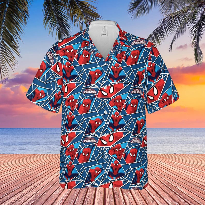 K&ouml;nnte beinhalten: Kurz&auml;rmeliges Hemd mit einem sich wiederholenden Muster von Spider-Man in Rot und Blau. Das Hemd hat einen wei&szlig;en Kragen. Der Hintergrund zeigt eine Strandszene mit Palmen und Meer.