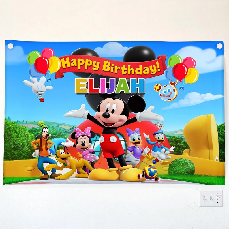 Pu&ograve; includere: Un banner colorato con Topolino e i suoi amici, con la scritta "Happy Birthday! ELIJAH". Il banner include immagini di palloncini, una casa rossa e altri personaggi dei cartoni animati su uno sfondo di cielo blu.