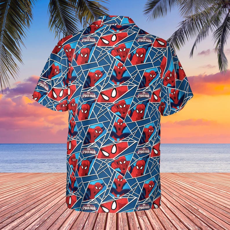 K&ouml;nnte beinhalten: Blaues kurz&auml;rmeliges Button-Down-Hemd mit einem sich wiederholenden Muster von Spider-Man in roten und blauen geometrischen Formen. Das Hemd enth&auml;lt den Text "Spider-Man" in Wei&szlig;. Das Hemd wird auf einem Holzdeck mit Strand und Sonnenuntergang im Hintergrund pr&auml;sentiert.