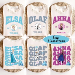 Puede incluir: Seis camisetas color crema con diferentes dise&ntilde;os con personajes de la pel&iacute;cula Frozen. Cada camiseta tiene el nombre de un personaje, una imagen y el texto "EST 2013" y "YOUR NAME". Tambi&eacute;n est&aacute; presente el texto "Any Characters".