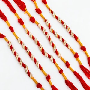 May include: Five decorative bracelets featuring twisted red and yellow thread strands accented with small white beads. Each bracelet includes knotted sections and ends with loose red thread tassels, creating a uniform and symmetrical design.