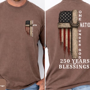 May include: A brown short-sleeve t-shirt featuring a graphic of a wooden cross overlaid on a distressed American flag. The text reads One Nation Under God and 250 Years of Blessings. The front has a small version, and the back has a large version.