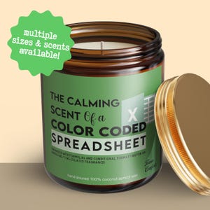 May include: A brown glass jar candle with a gold lid, labeled "The Calming Scent of a Color Coded Spreadsheet." The label is green with white text and a spreadsheet graphic. The candle is hand-poured with coconut apricot wax. A green starburst graphic says "multiple sizes & scents available!"
