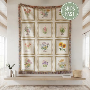 Op de afbeelding: Een beige sprei met een bloemenontwerp. De sprei heeft een raster van bloemenillustraties in postzegelachtige kaders. Elk kader bevat een ander bloemstuk en een naam. De sprei heeft een gefranjerde rand en de tekst "SHIPS FAST".